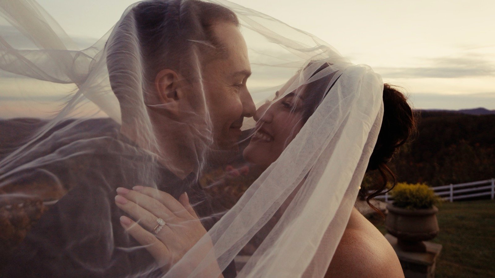 A couple sharing a quiet moment beneath a veil at golden hour
